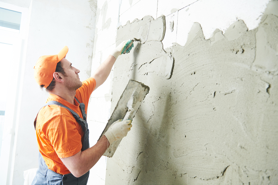 man putting cement on the wall